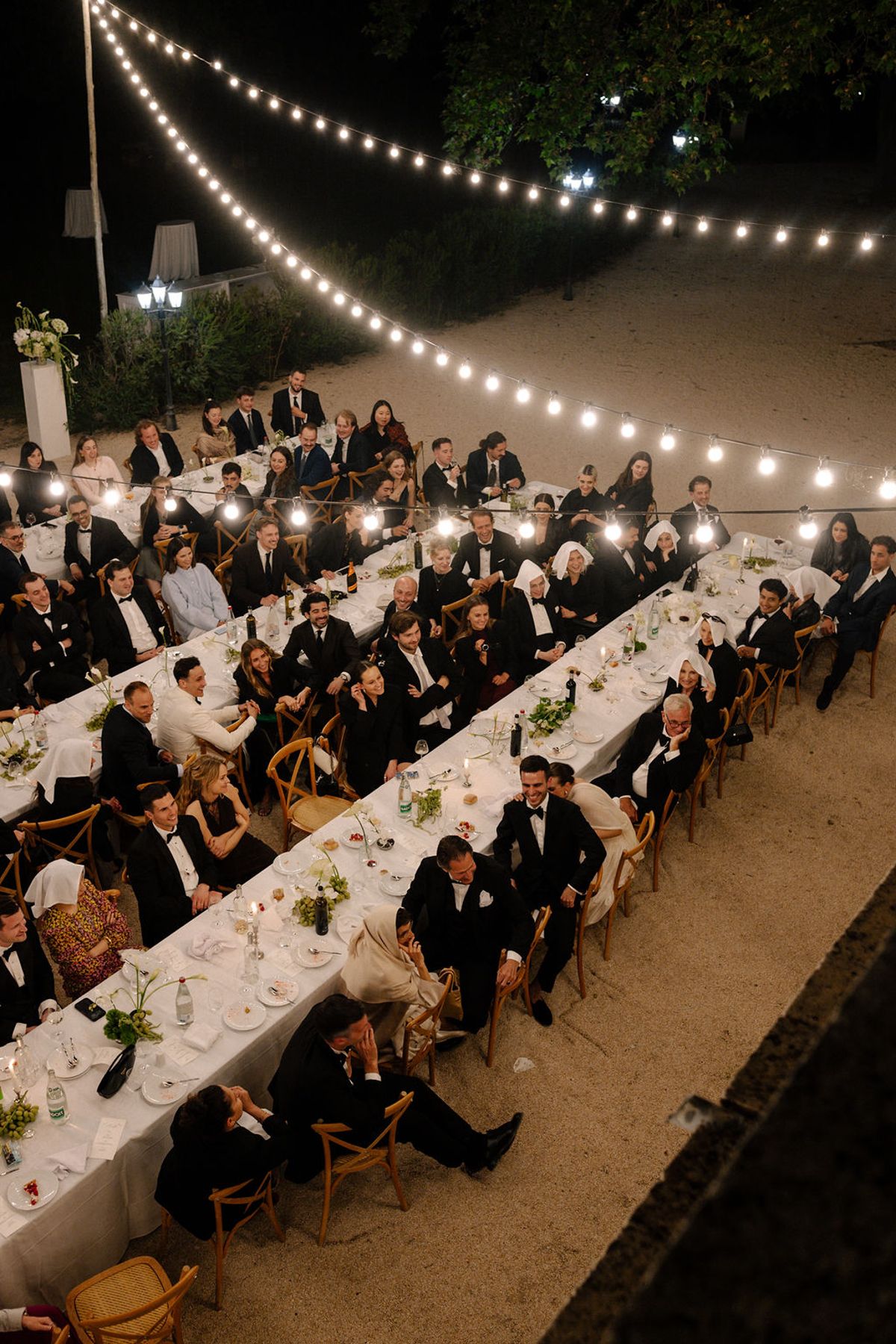 The long reception tables lit by string lights at dusk