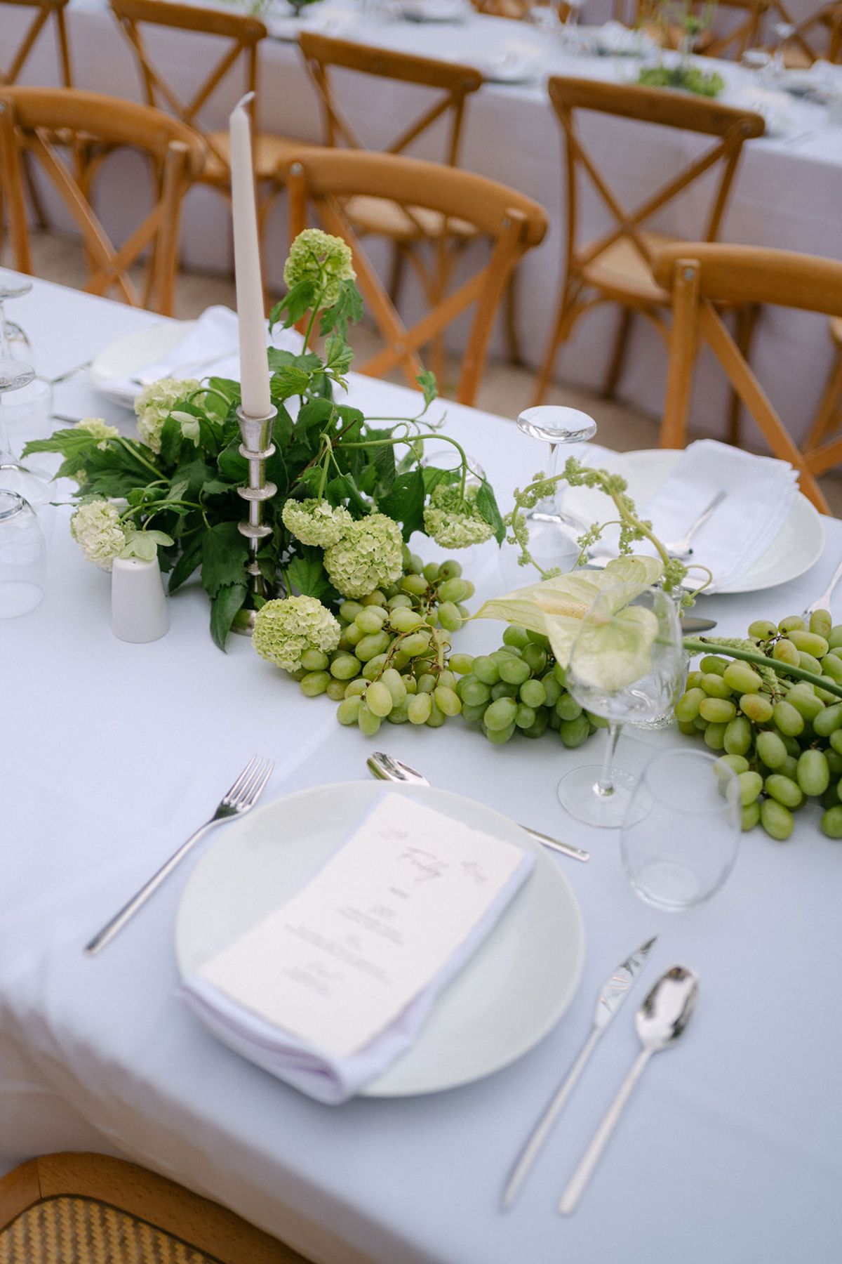 A table setting with grapes and greenery trailing across the linen