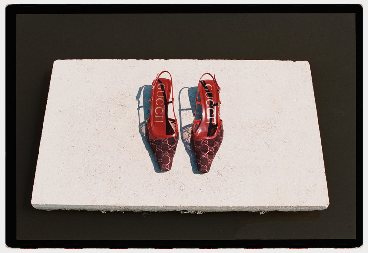 Red slingback shoes on a white stone block, in a black film-frame border