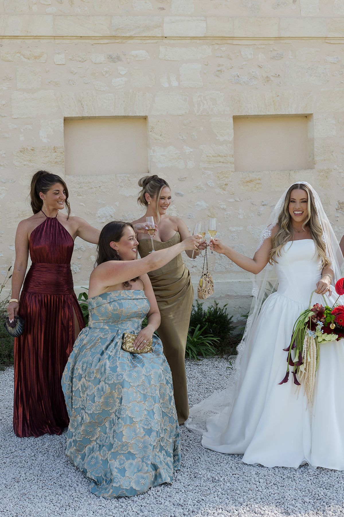 Kendra toasting with her bridesmaids in front of the stone château wall