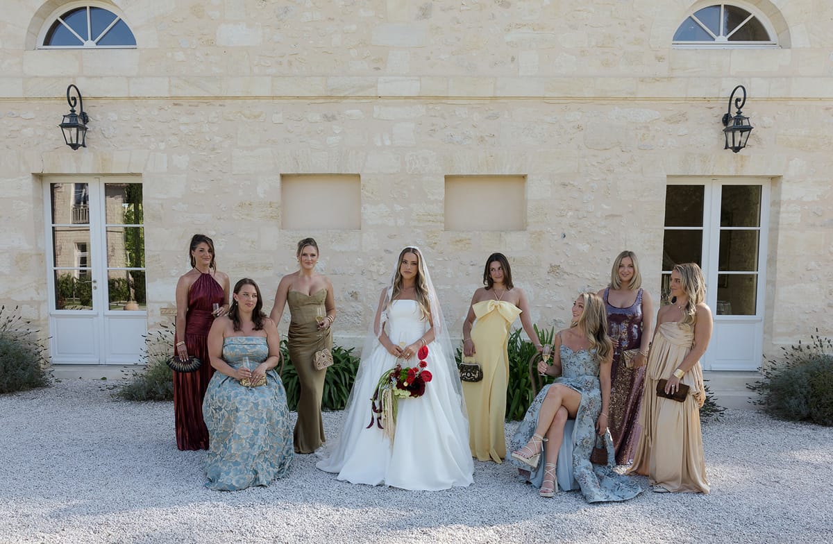 Kendra with her bridesmaids in mismatched long dresses outside the château