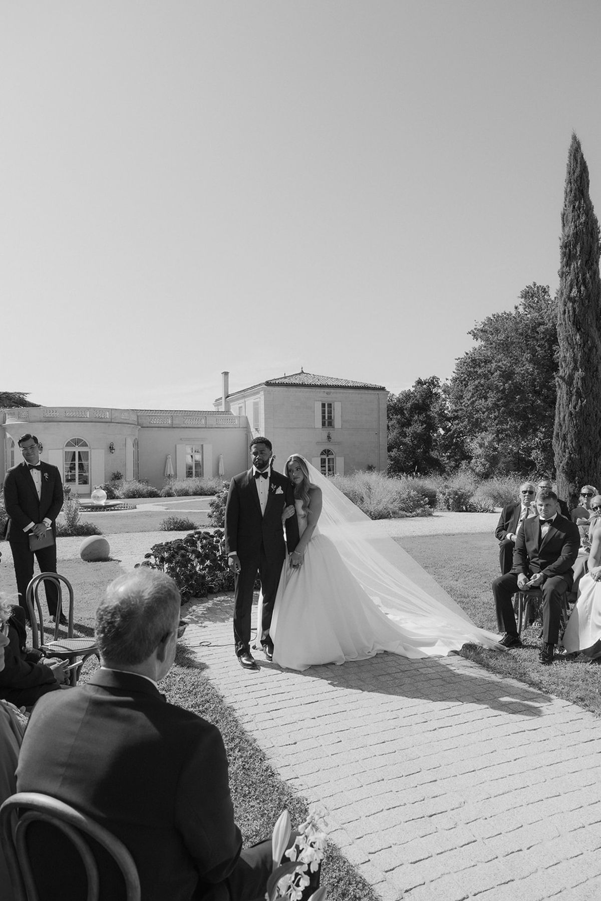 Kendra and Brandon walking up the aisle among the guests, black and white