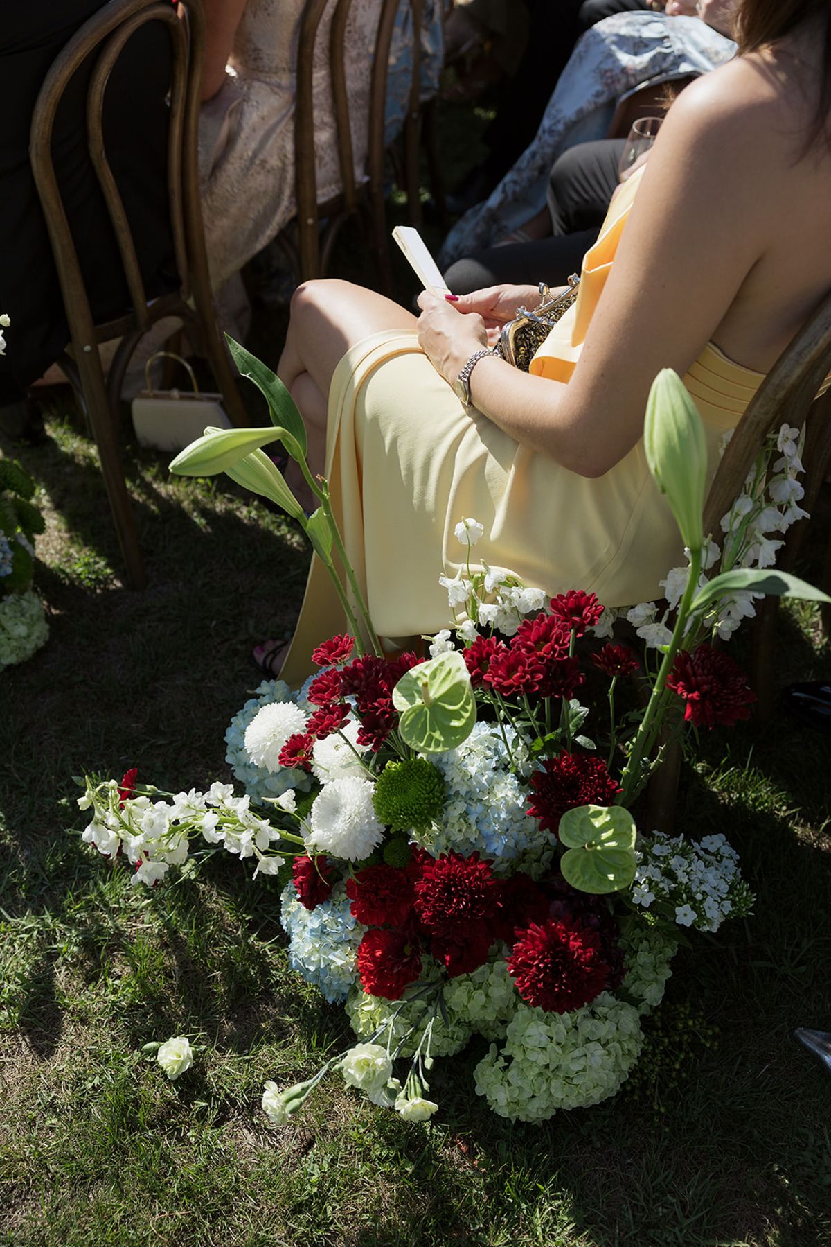 A guest reading the order of service beside red and white aisle flowers