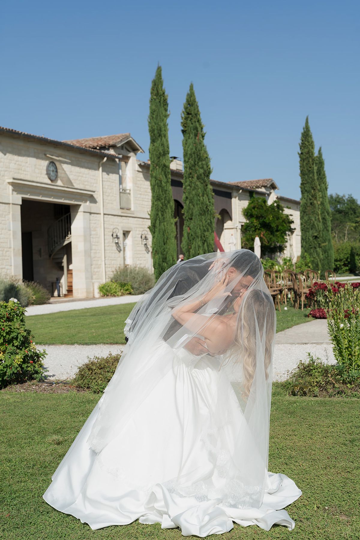 Kendra and Brandon kissing under her veil in the garden