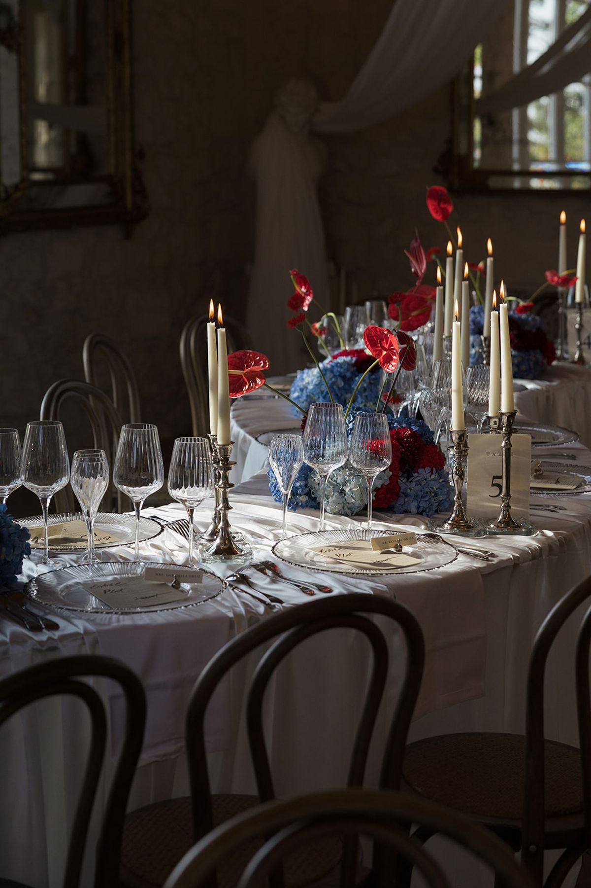 A table set with candlesticks, glassware and red and blue flowers