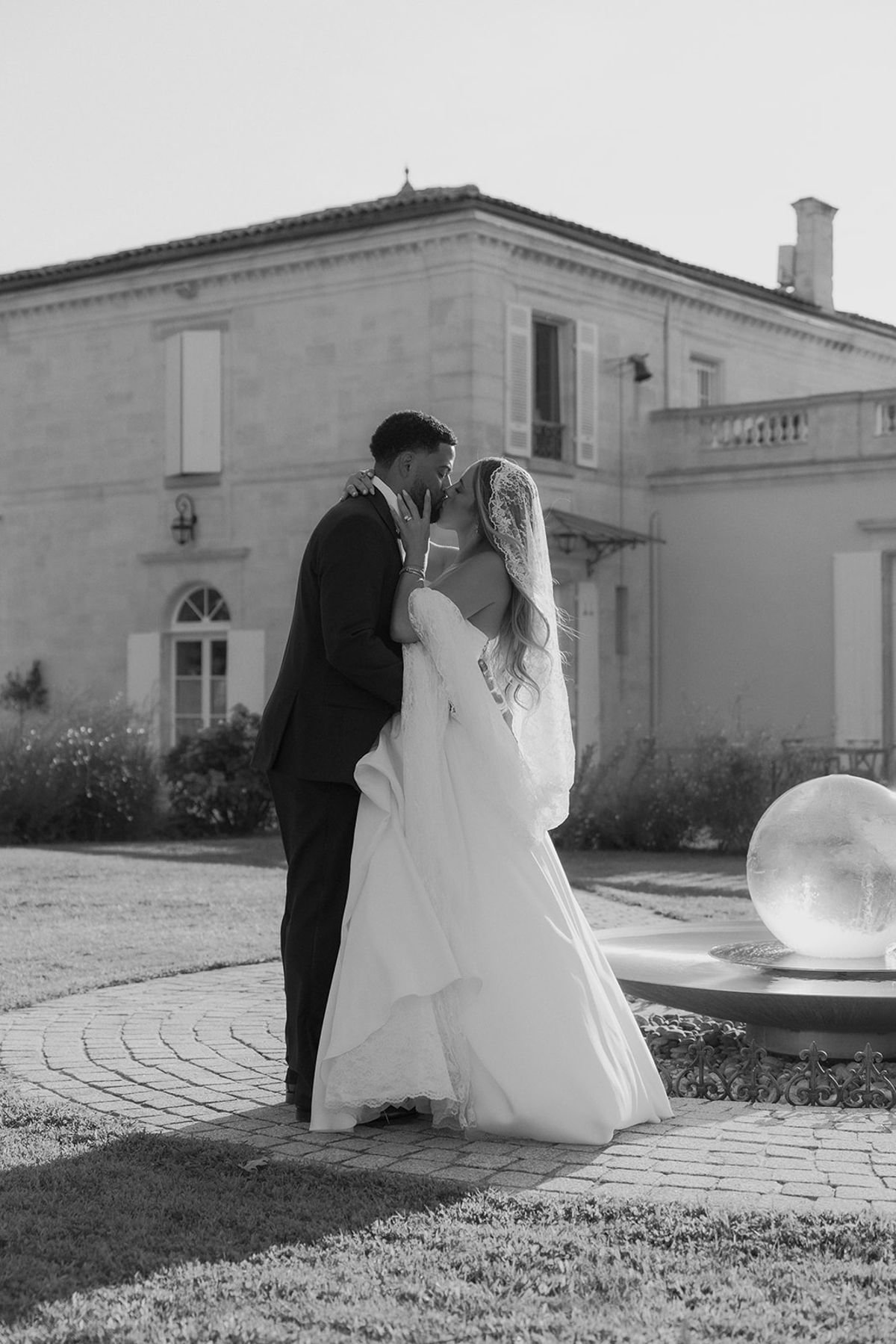 Kendra and Brandon kissing beside the fountain at Château Gassies