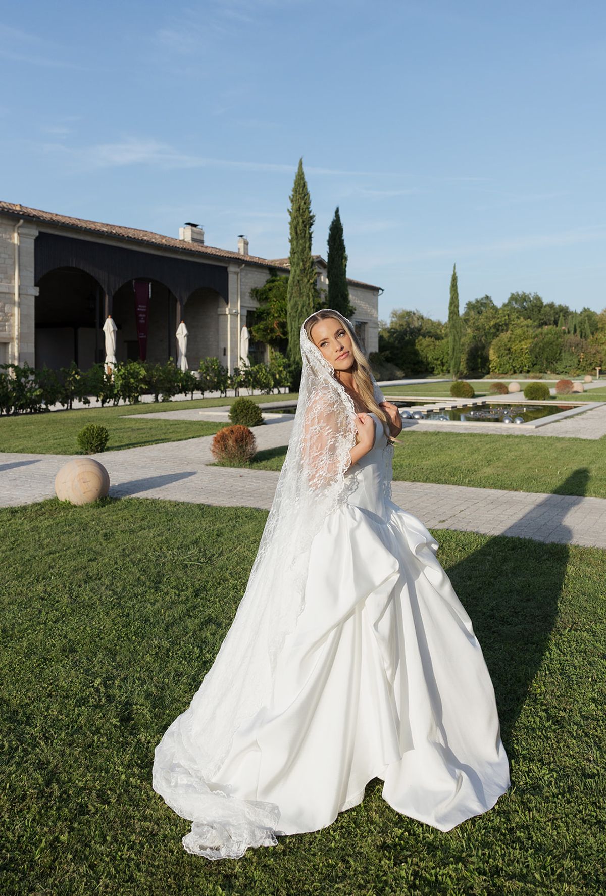 Kendra on the lawn in her gown and veil, the château behind