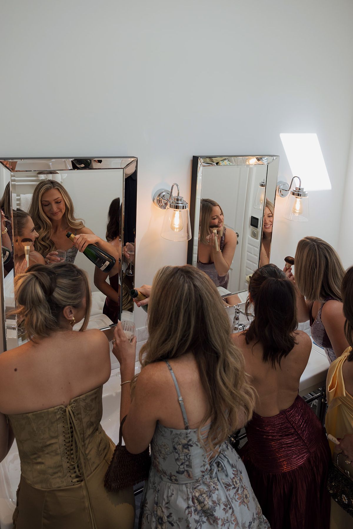 Bridesmaids getting ready in front of a row of mirrors