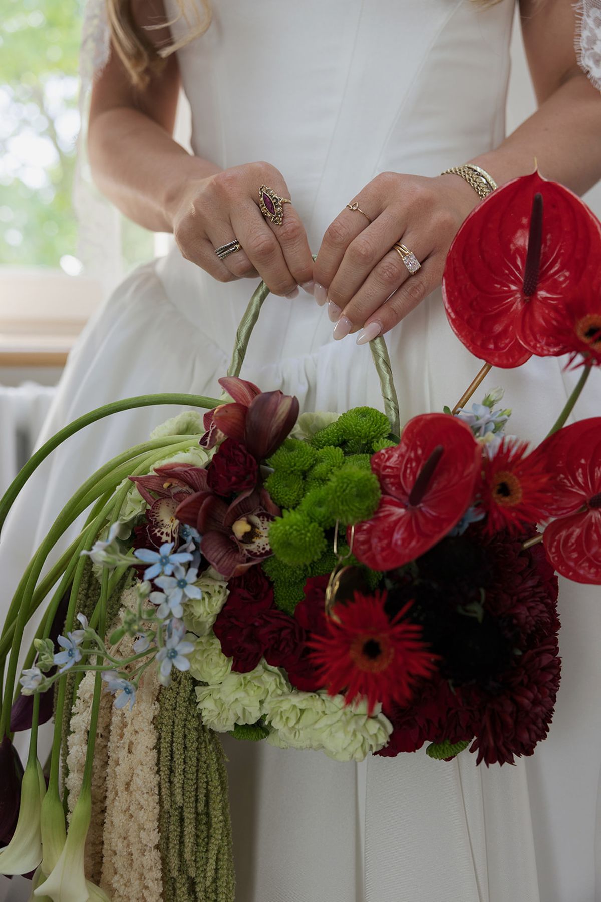 Kendra holding her bouquet of red anthuriums, green chrysanthemums and blue flowers
