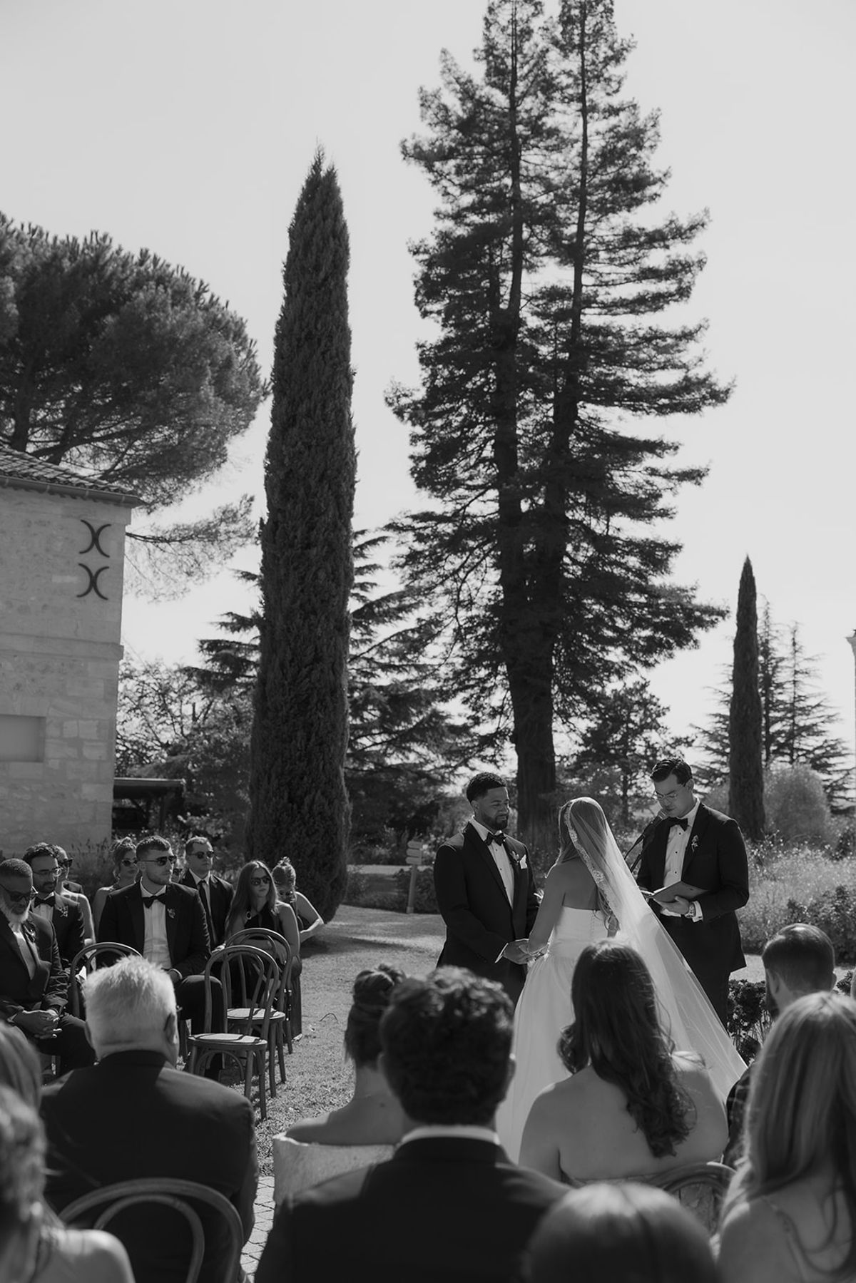 Kendra and Brandon at the ceremony seen past the guests, black and white