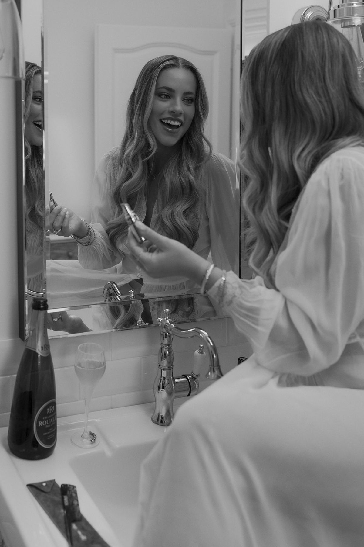 Kendra smiling at her reflection while getting ready, black and white