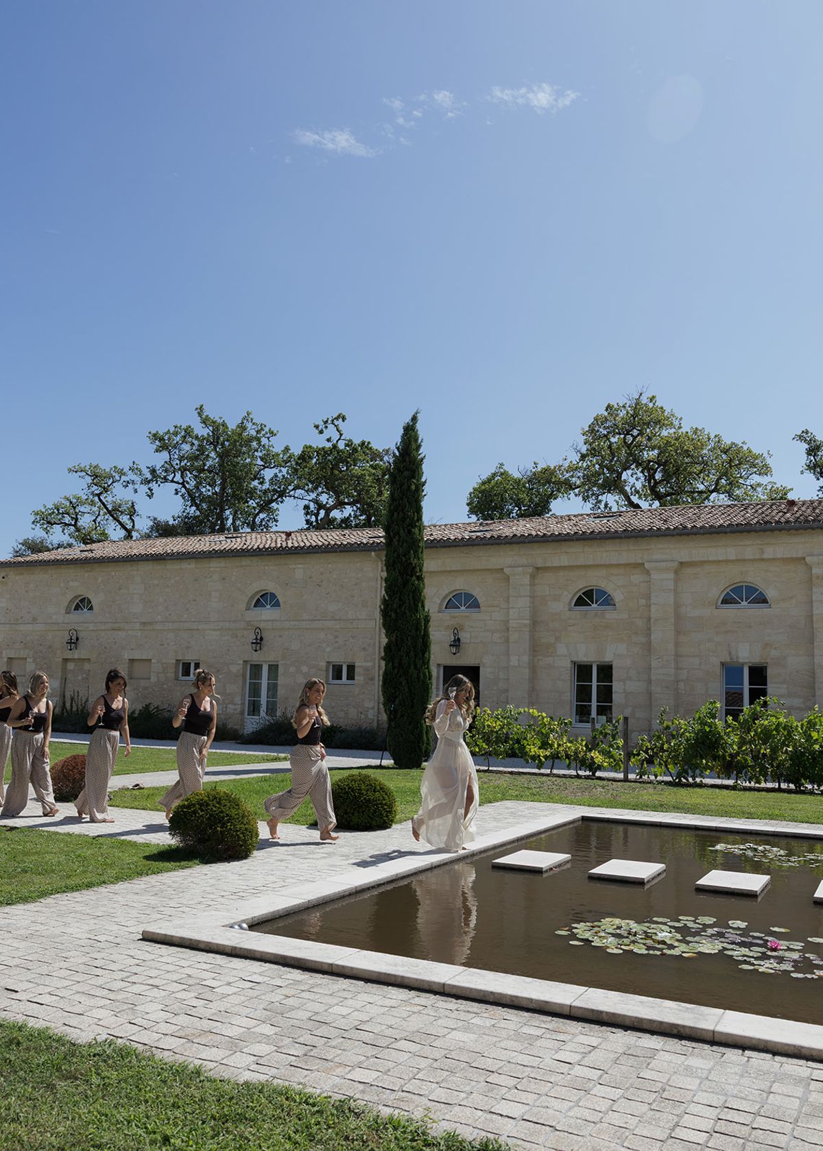 Bridesmaids walking past the formal pond