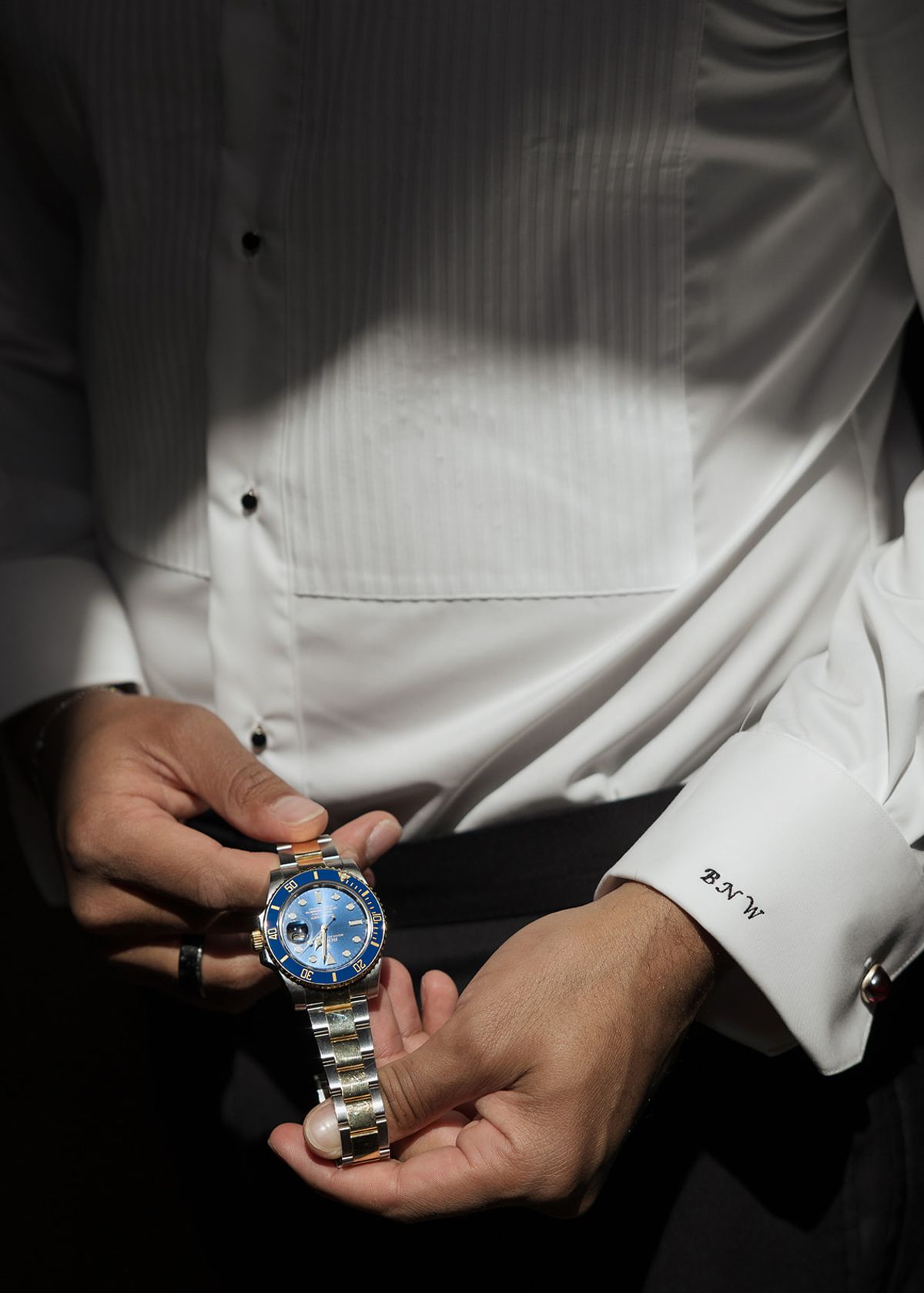Brandon holding his watch, his cuff monogrammed