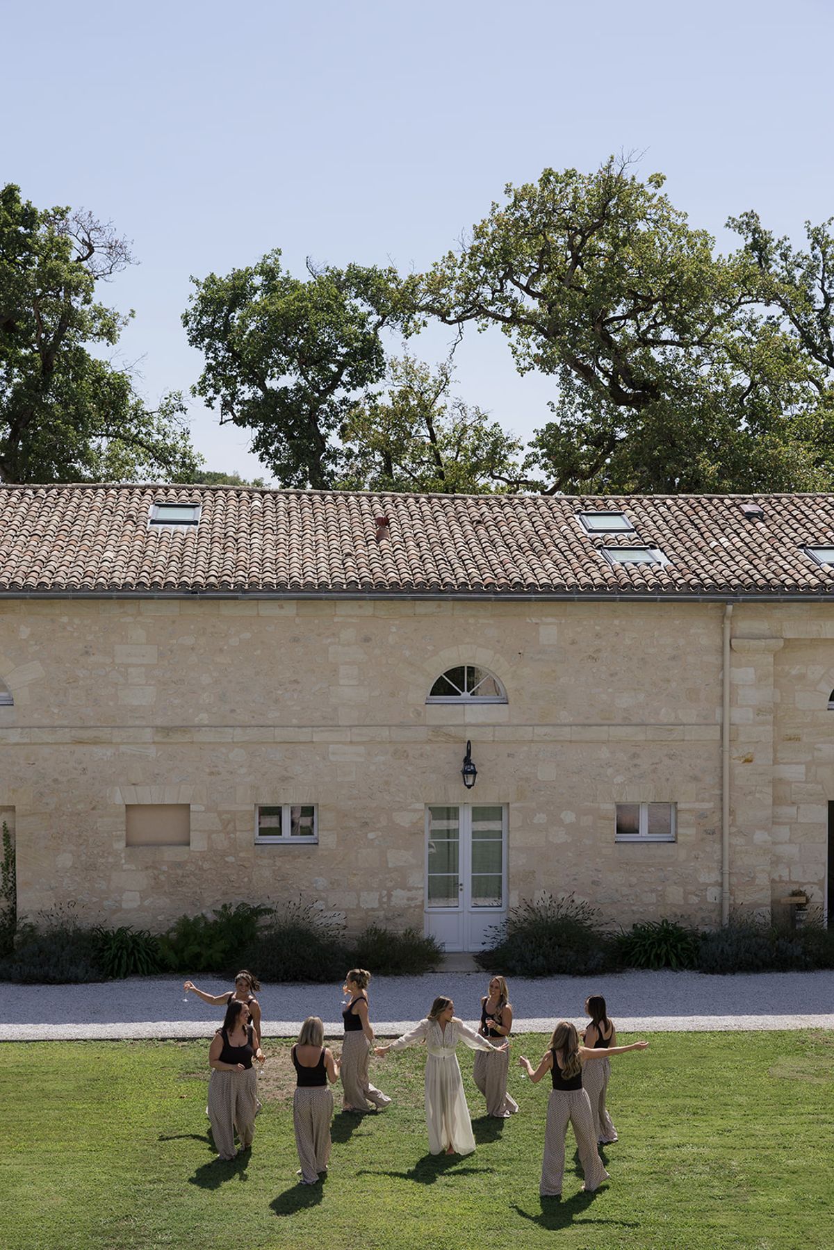 Bridesmaids walking across the lawn in front of the stone outbuildings