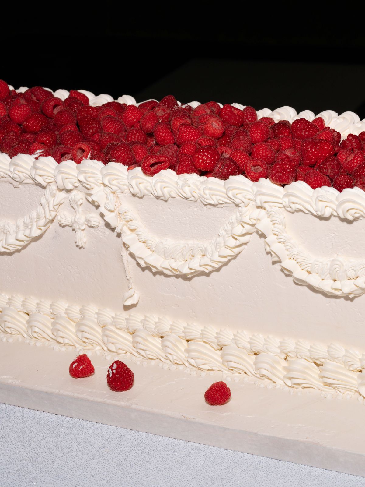 Detail of the piped cream wedding cake topped with raspberries