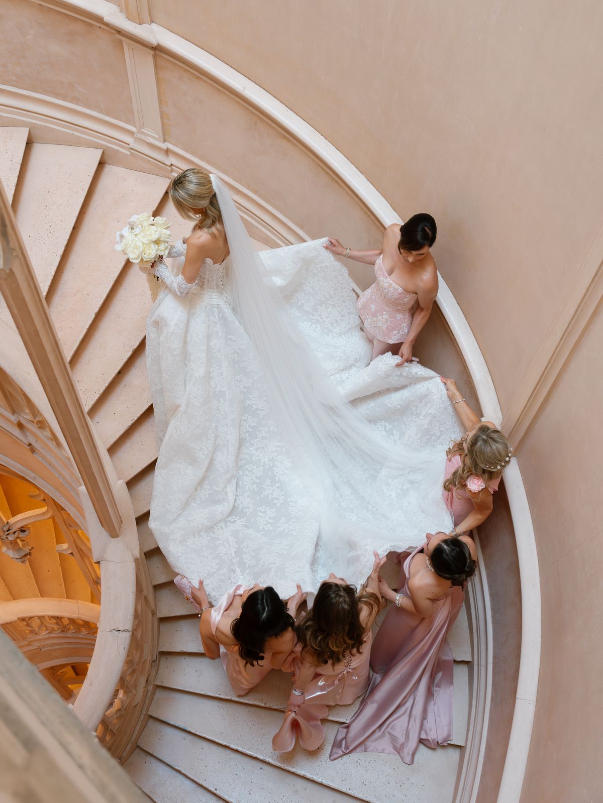 Overhead view of Kira and her bridesmaids in pink on the spiral staircase at Chateau Challain