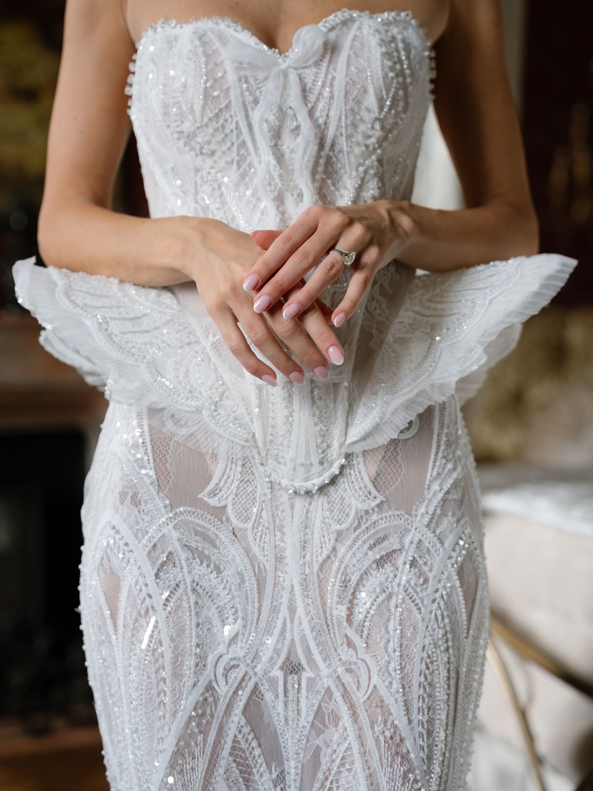 Close-up of Kira's hands and engagement ring against her pearl-beaded corset