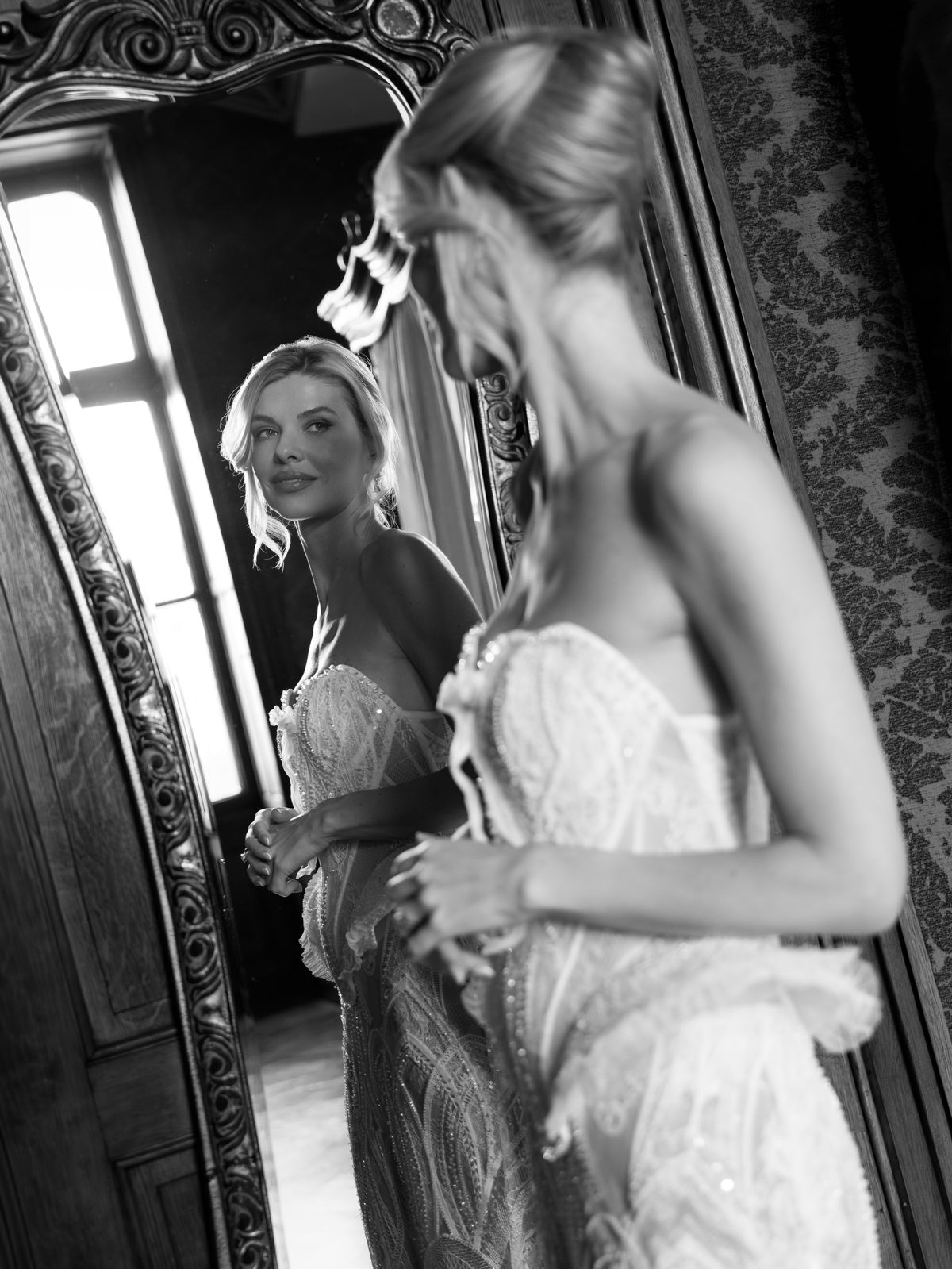 Kira is laced into her corset in front of a carved mirror at Chateau Challain
