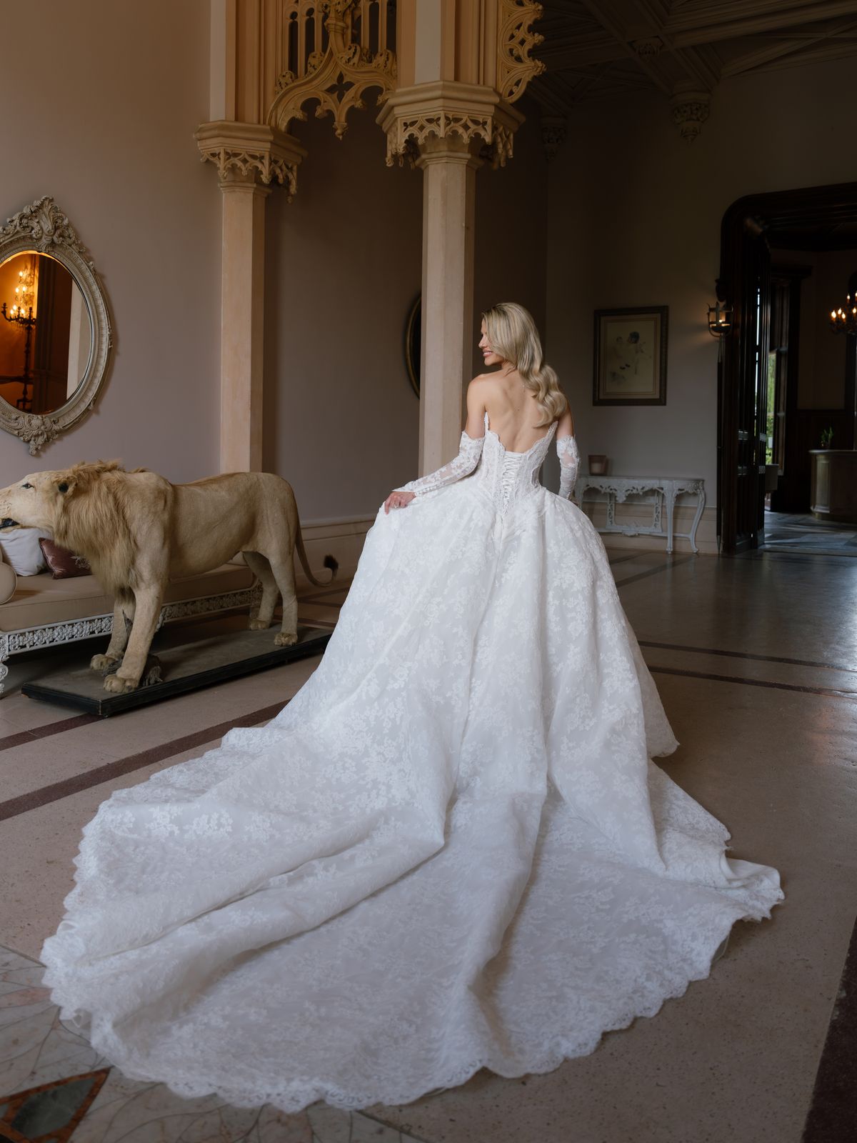 Kira in her lace ball gown with a long train in the Gothic hall of Chateau Challain