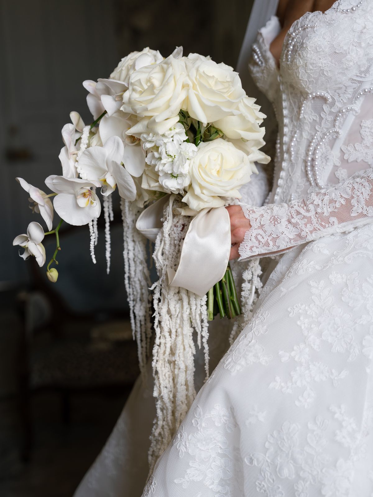 Close-up of Kira's white rose, orchid and amaranthus bouquet against her lace gown