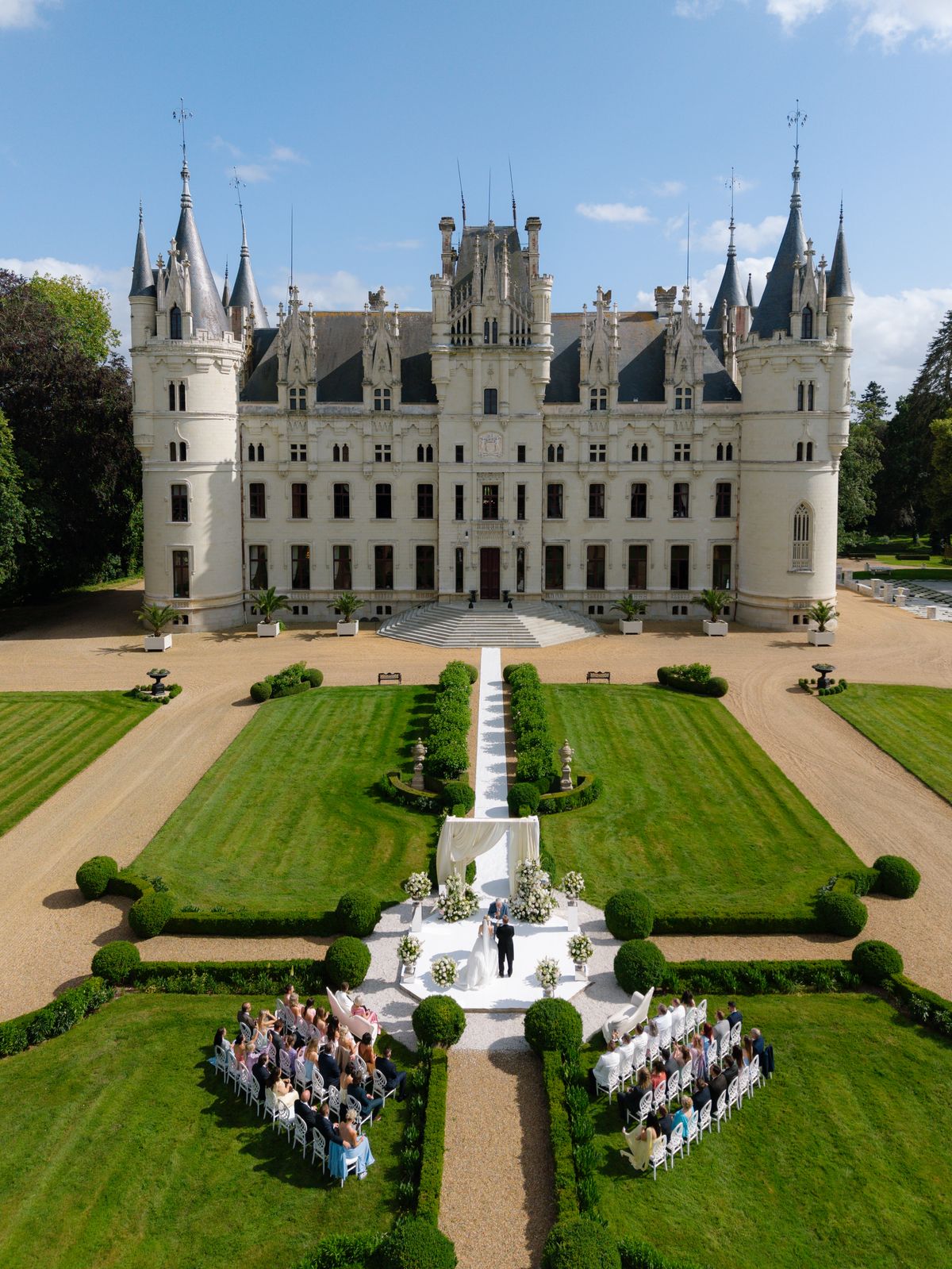Aerial view of guests seated either side of the aisle for the ceremony in the gardens of Chateau Challain