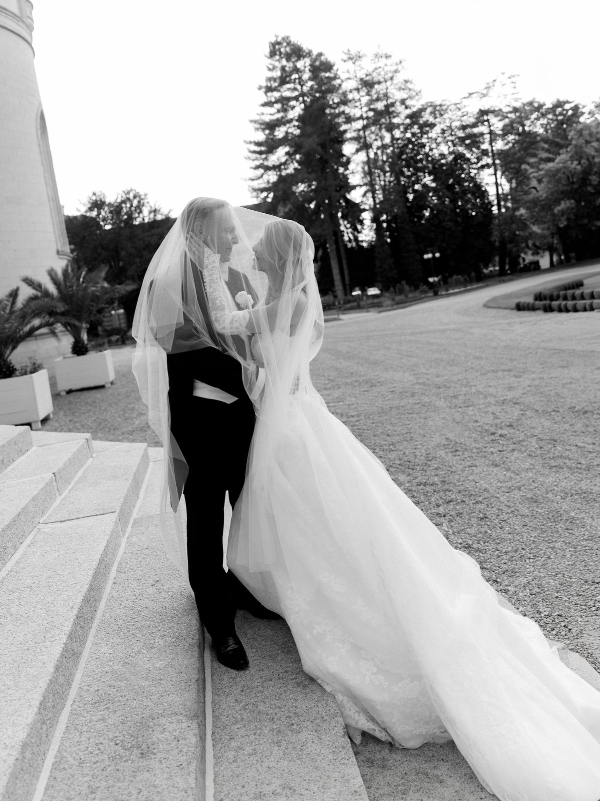 Kira and Steve kiss under her veil on the stone steps of Chateau Challain