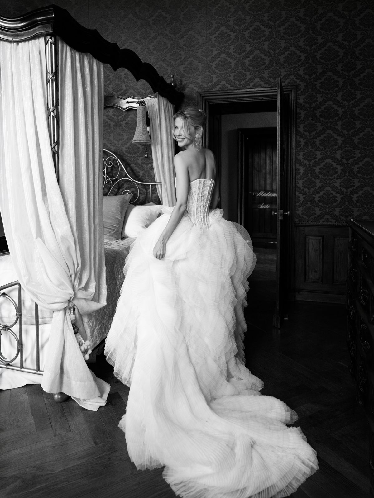 Kira in a ruffled tulle gown looks back over her shoulder in a canopy bedroom at Chateau Challain