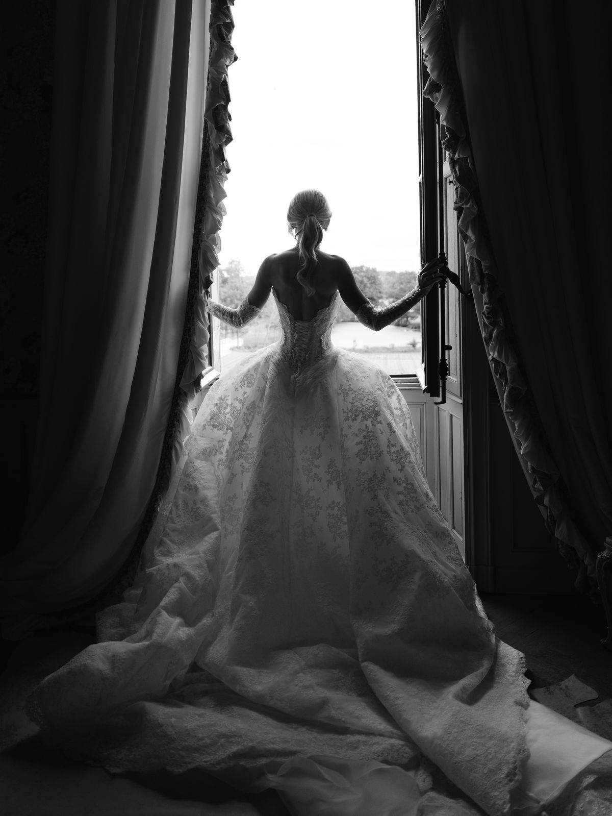 Kira silhouetted in an open window of Chateau Challain with her gown spread behind her
