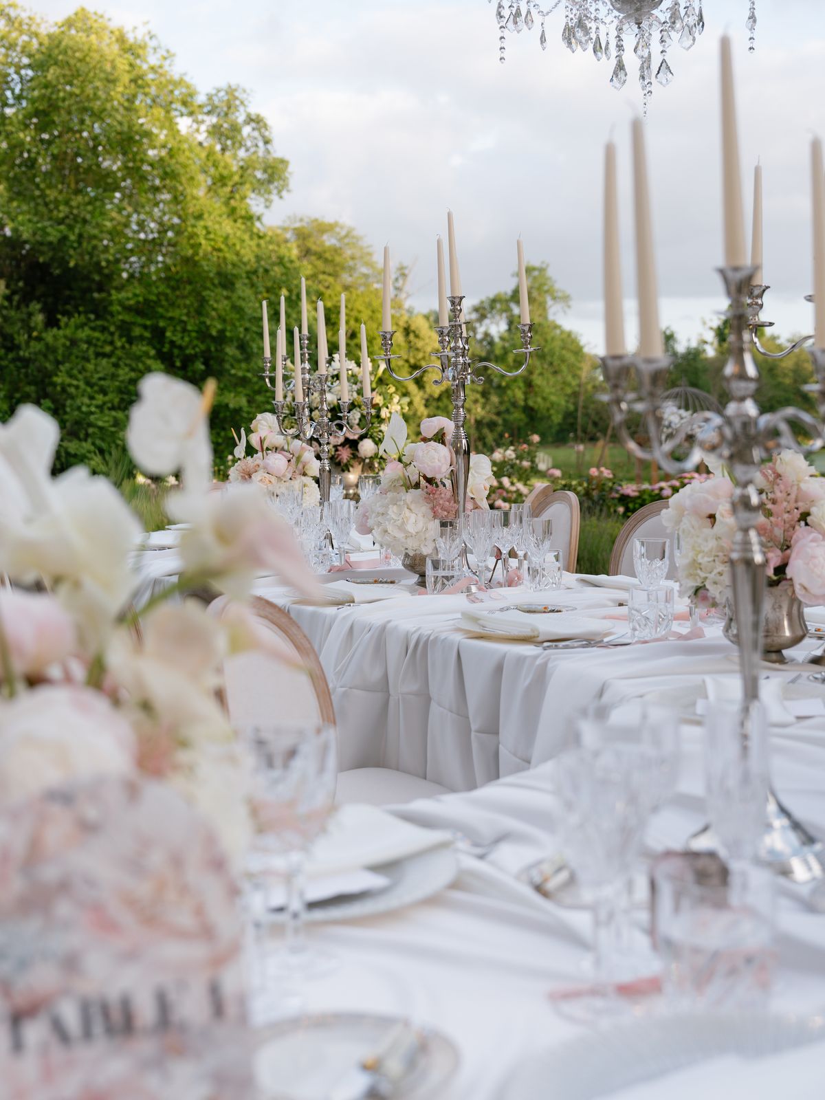 Long dinner tables with silver candelabras and blush florals on the lawn at Chateau Challain