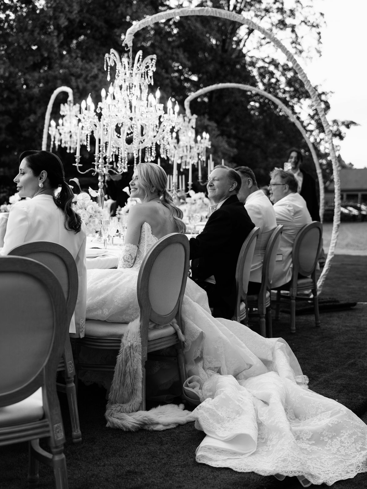 Guests seated at dinner beneath a chandelier arch on the lawn at Chateau Challain