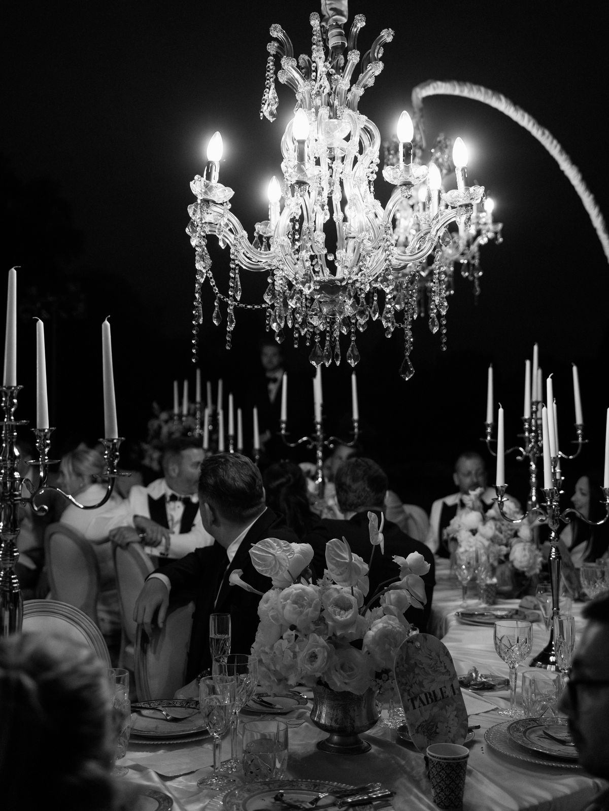 Guests at candlelit dinner tables beneath crystal chandeliers at Chateau Challain