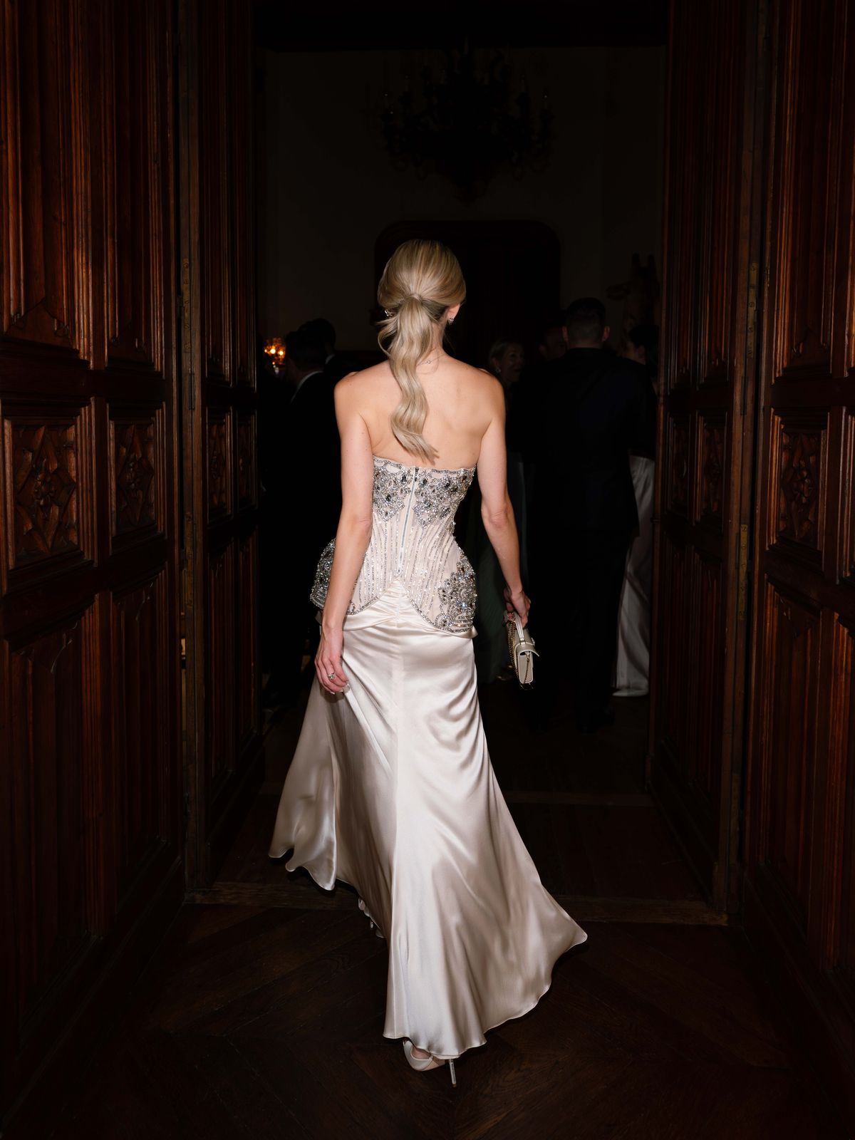 Kira walks through a dark panelled doorway at Chateau Challain in her evening gown