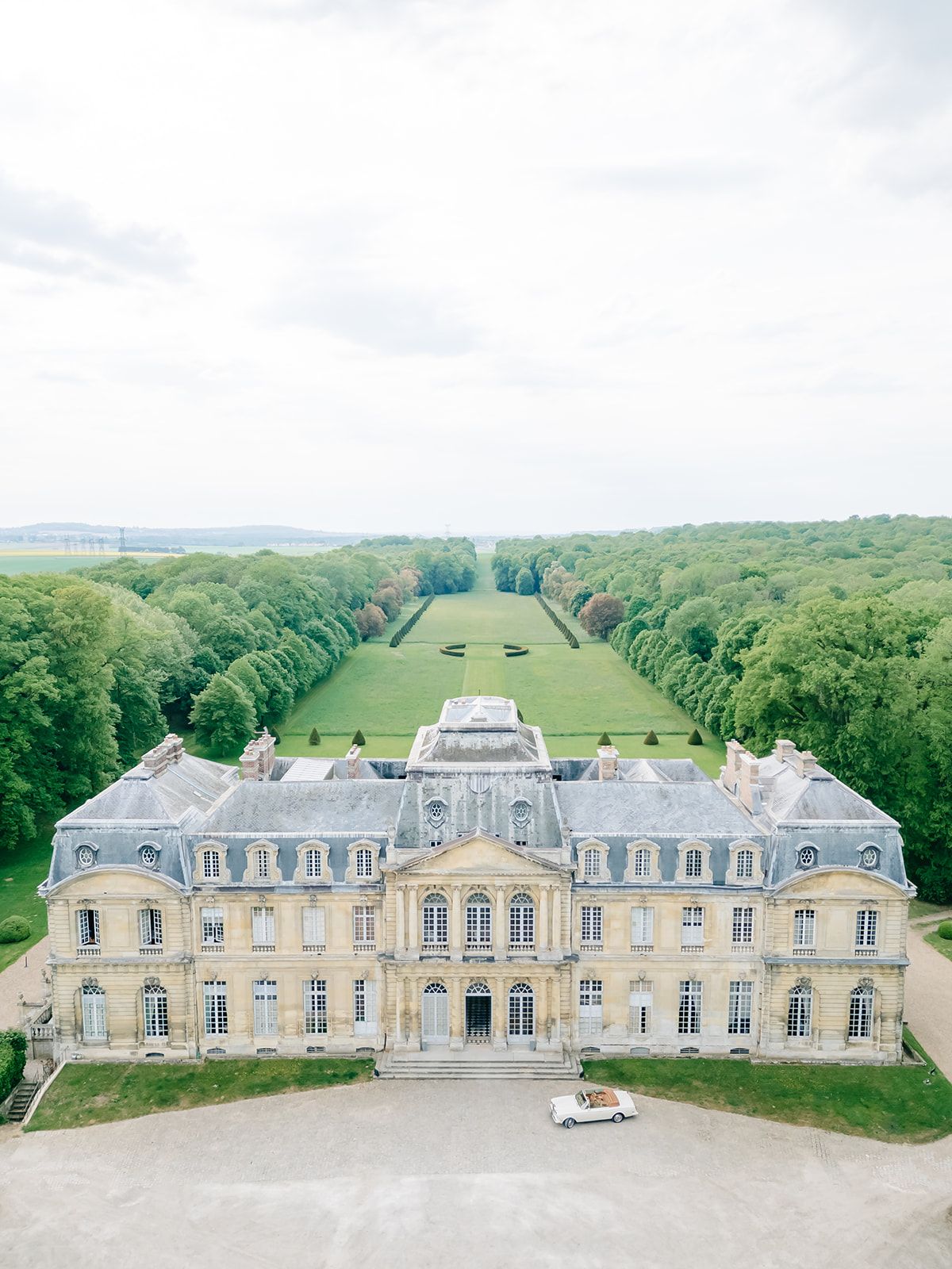 Wide view of Château de Champlâtreux and its formal gardens