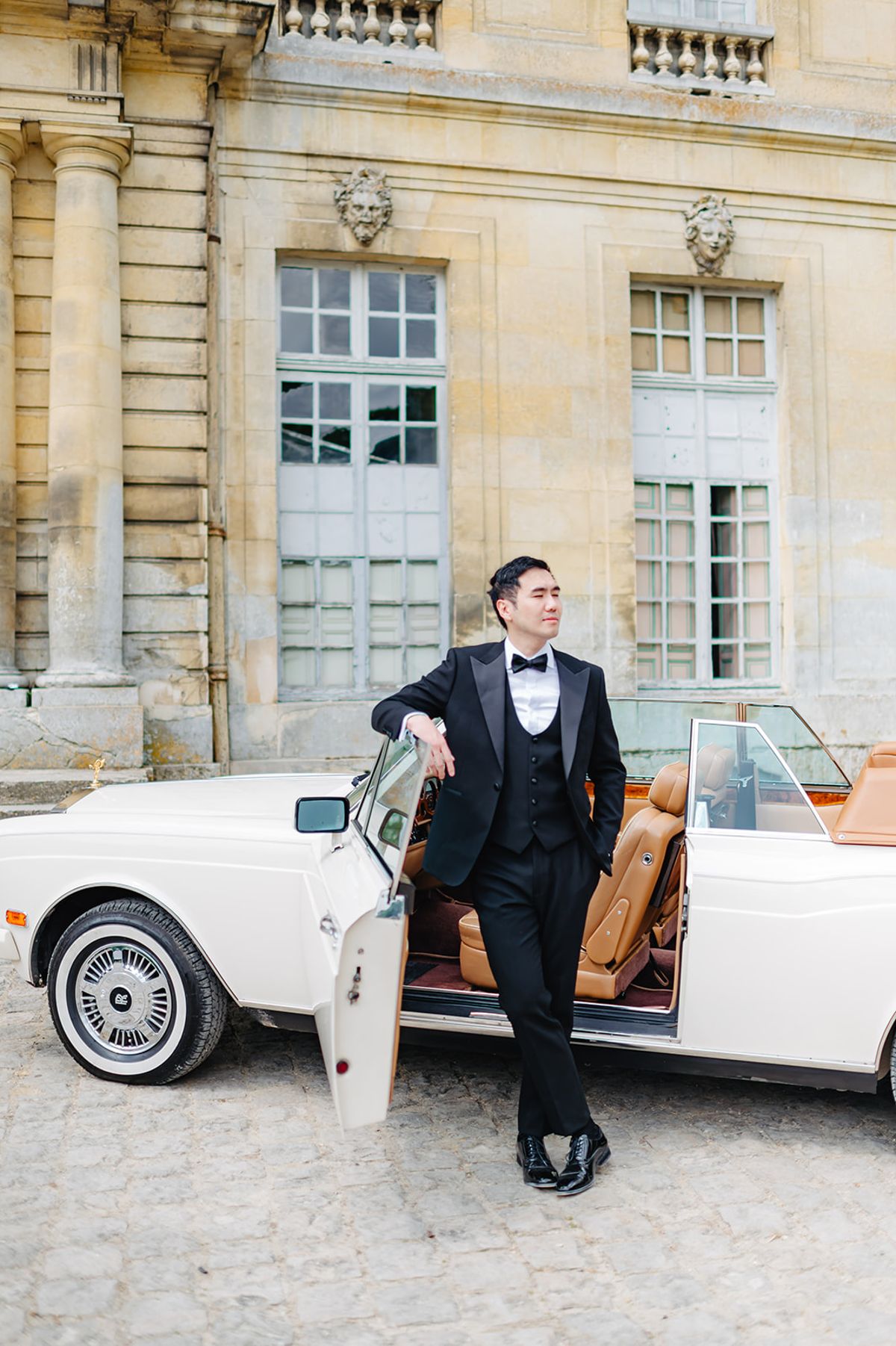Ruiji leaning against a vintage convertible while getting ready