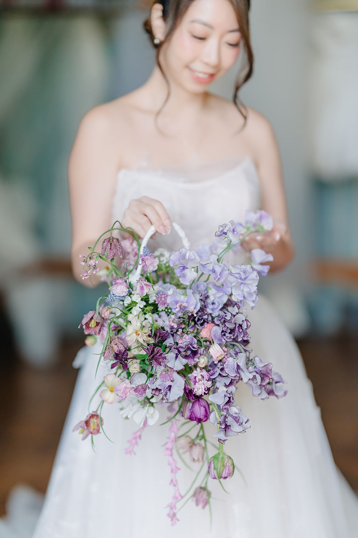 Close detail of Liana's hands holding her lilac and white bouquet