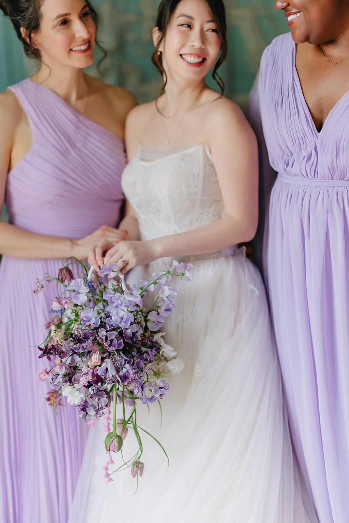 A bridesmaid in lilac holding her bouquet close