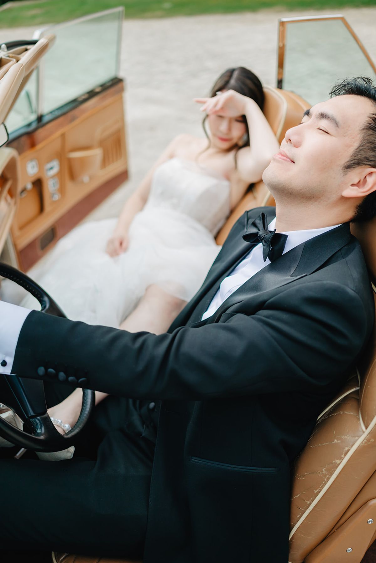 Ruiji leaning in close to Liana inside a vintage car