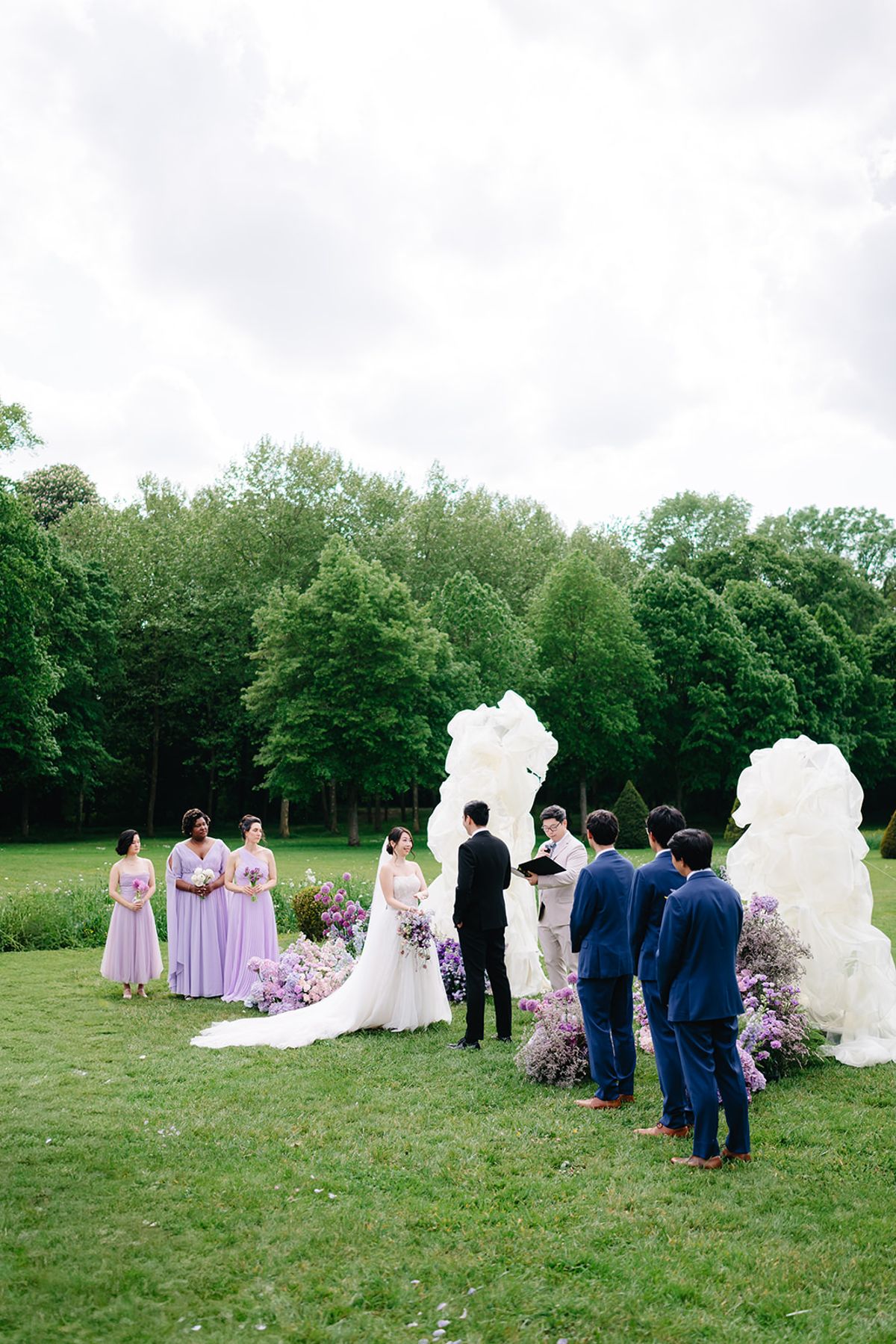 Wedding party and guests gathered beside the floral arch before the ceremony