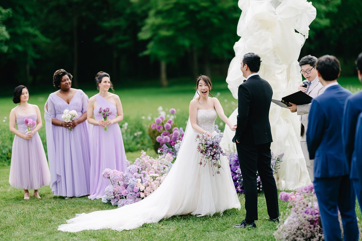 Liana and Ruiji exchanging vows beneath the floral arch with their wedding party