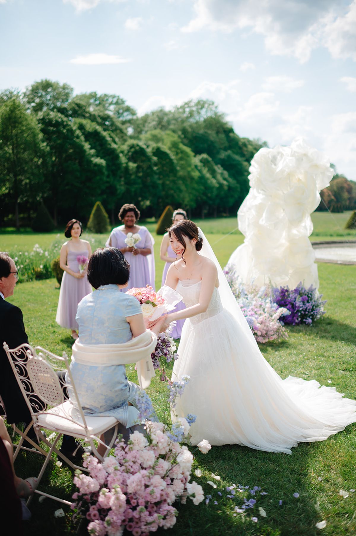 Bridesmaids in lilac gathered together beside the ceremony's floral installation