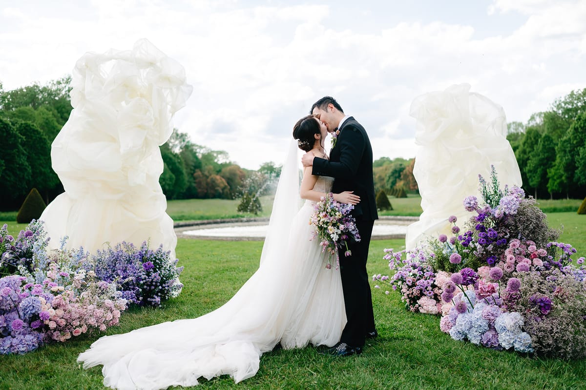 Liana and Ruiji kissing beneath the floral arch at the close of the ceremony