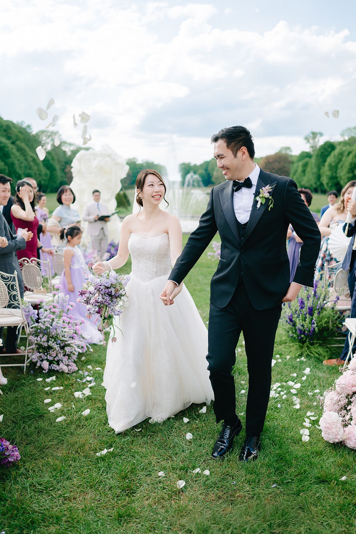 Liana and Ruiji walking hand in hand past seated guests during their ceremony