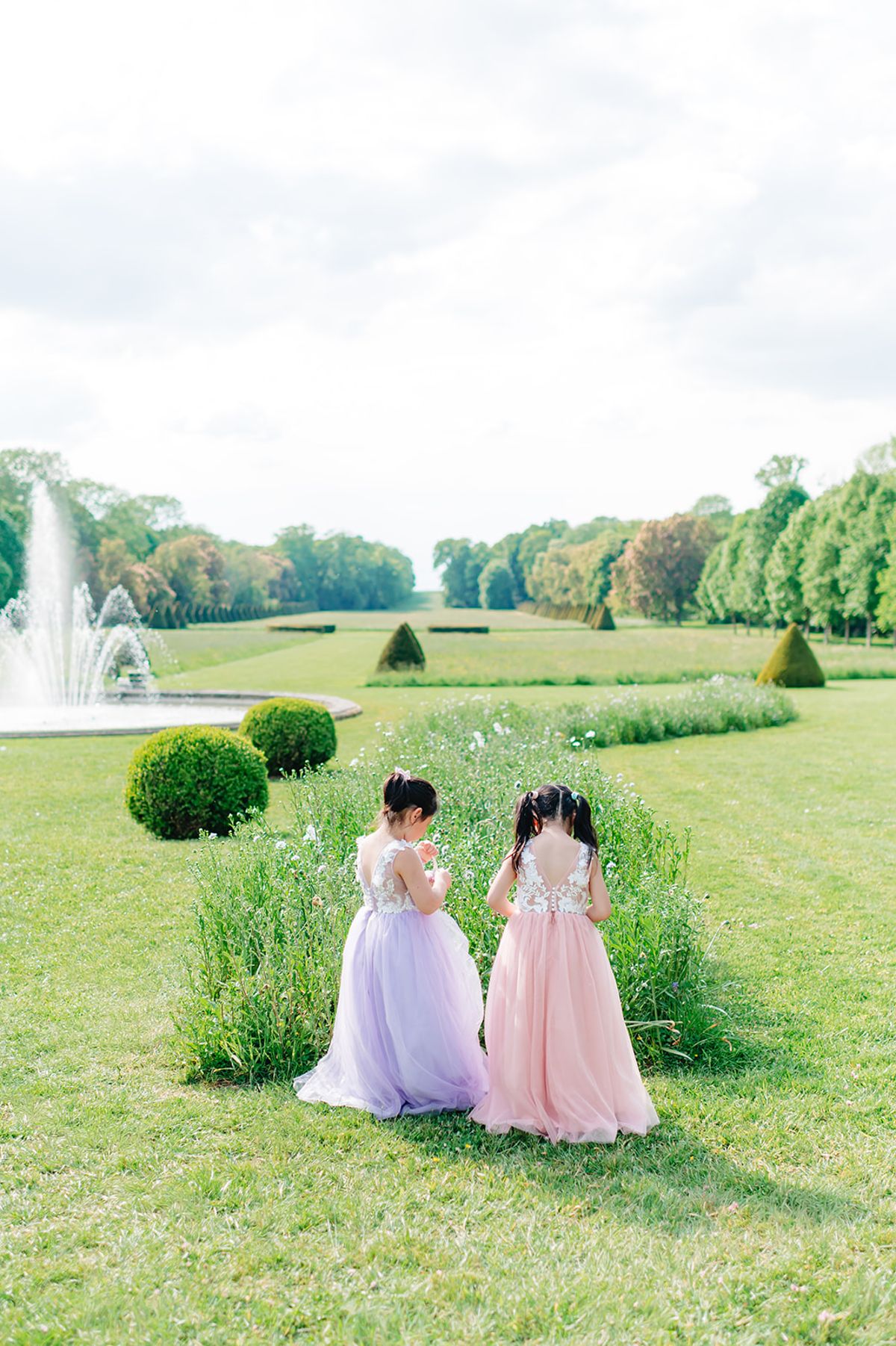 Bridesmaids and a flower girl in pastel dresses walking together near the fountain