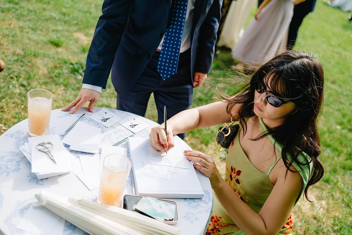Guests signing the guestbook during cocktail hour, drinks in hand