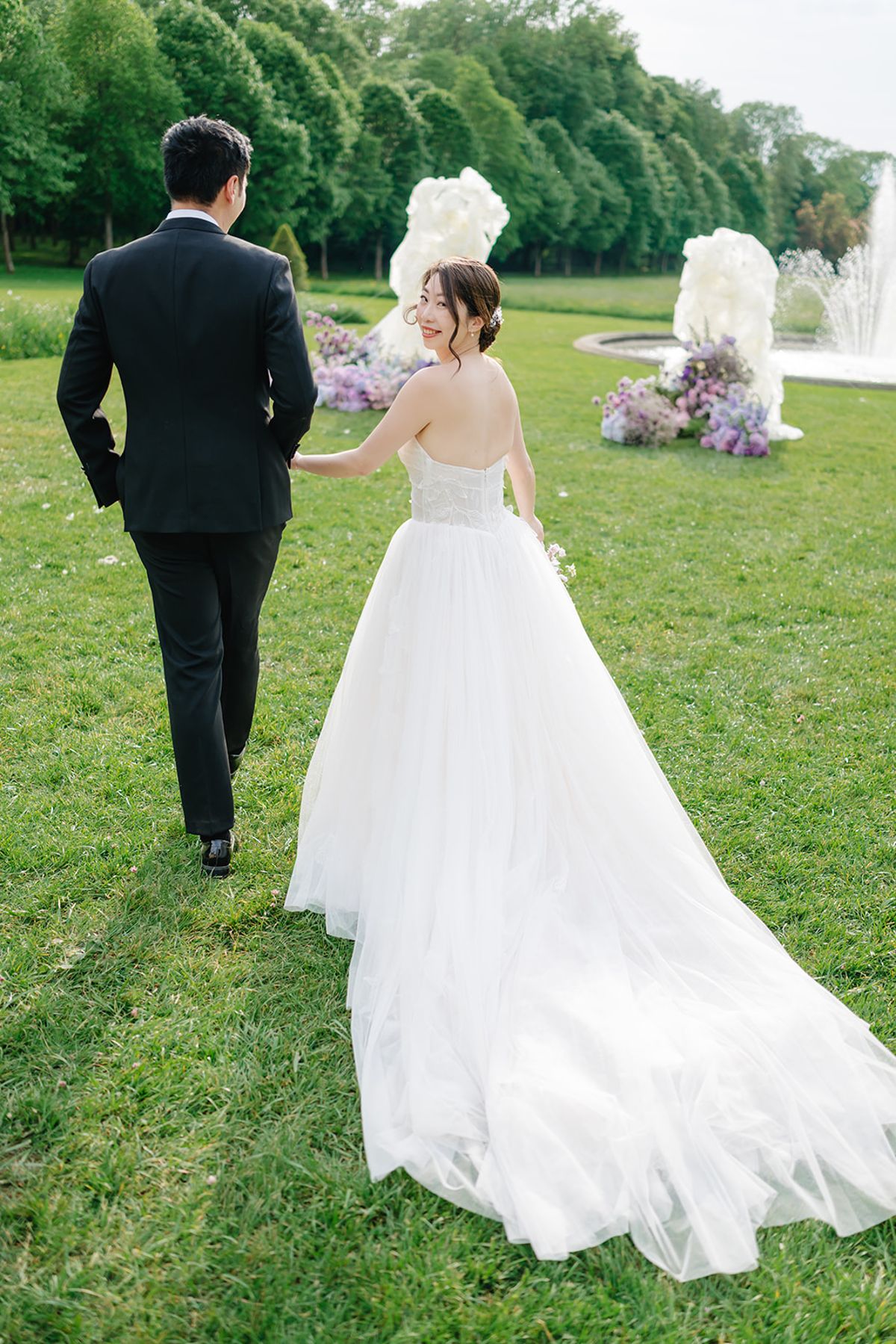 Liana and Ruiji walking hand in hand across the lawn, back view