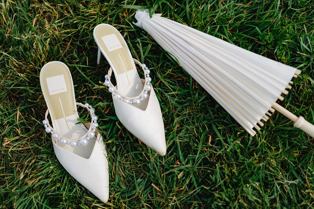 Liana's bridal shoes and a folding fan laid out on the grass