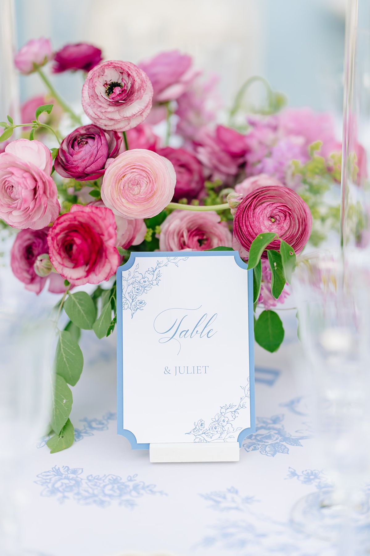 Pink and burgundy peony arrangement beside a hand-painted table card