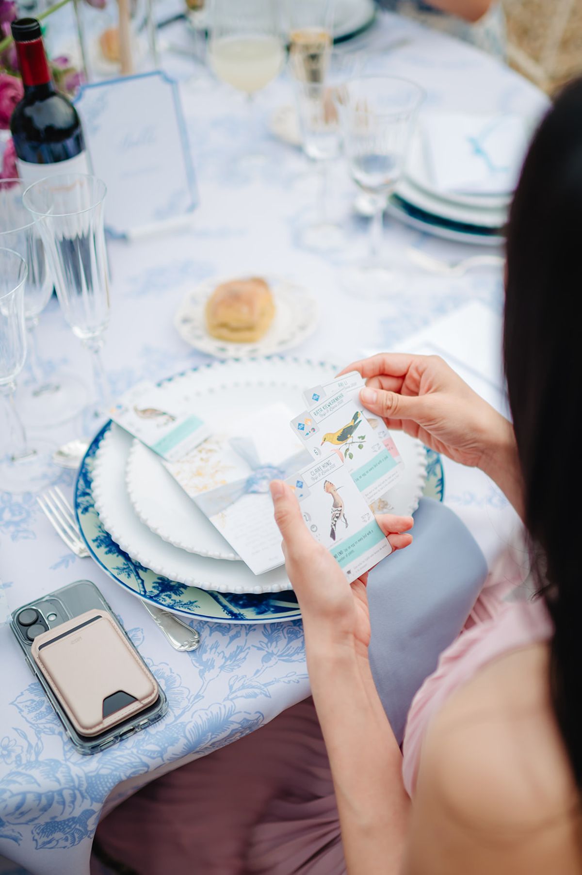 Hands holding an illustrated place card above the table setting