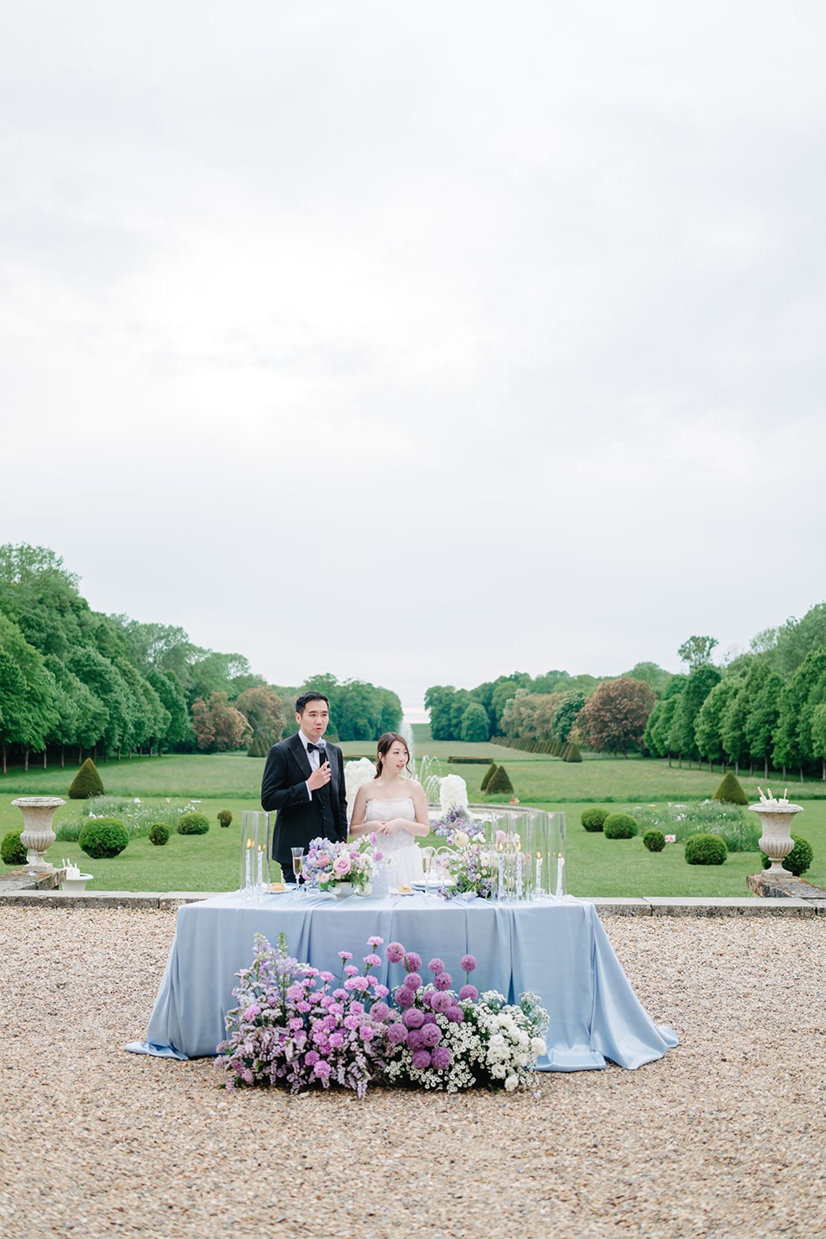 Liana and Ruiji walking together across the reception lawn with the fountain behind them