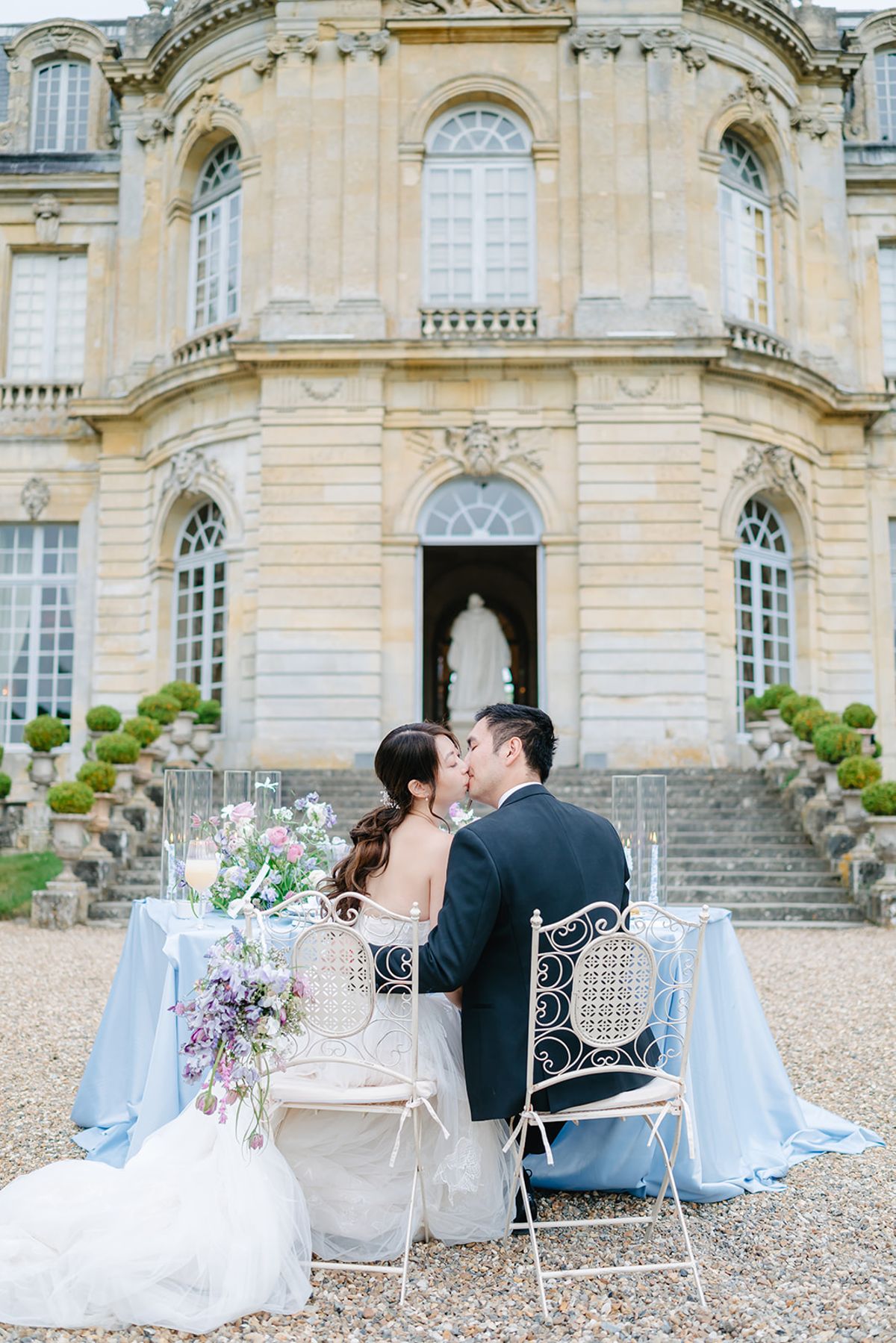 Liana and Ruiji seated at their sweetheart table on the Château de Champlâtreux steps
